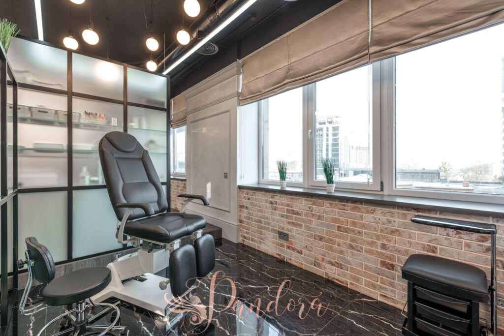 Black leather pedicure chair placed near brick wall in modern beauty salon with window and stylish i — Pandora Nail Spa, Lafayette, CA