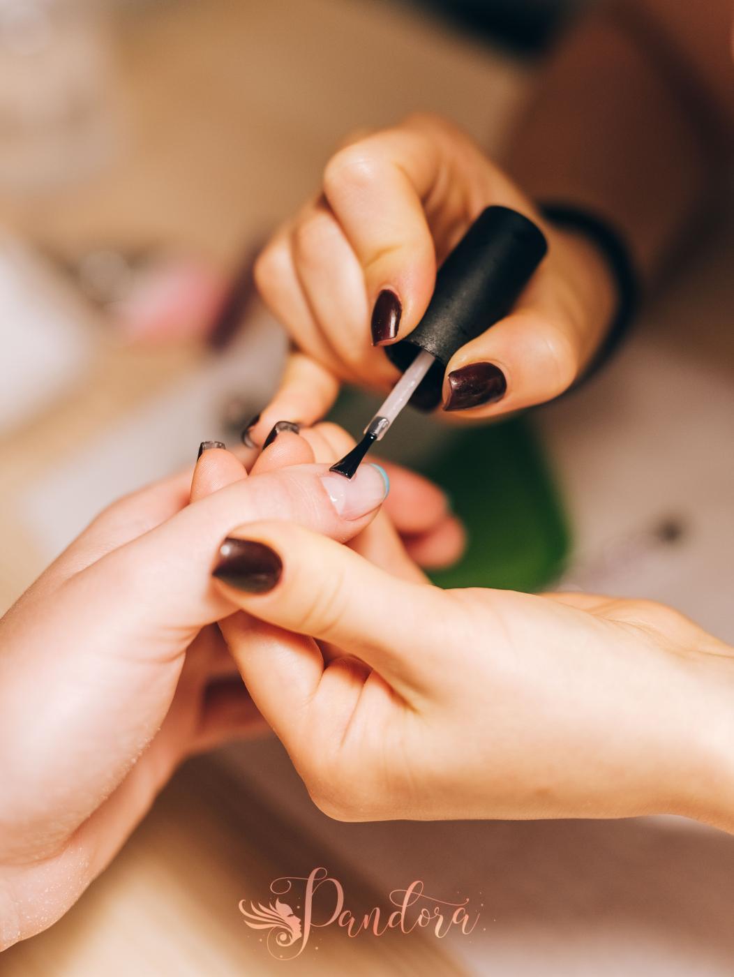 Close-up of a manicurist applying nail polish during a professional manicure session — Pandora Nail Spa, Lafayette, CA