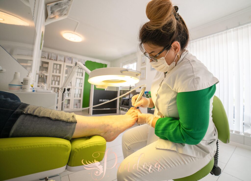 Side view of serious female in medical uniform and mask making hardware pedicure using modern equipm — Pandora Nail Spa, Lafayette, CA