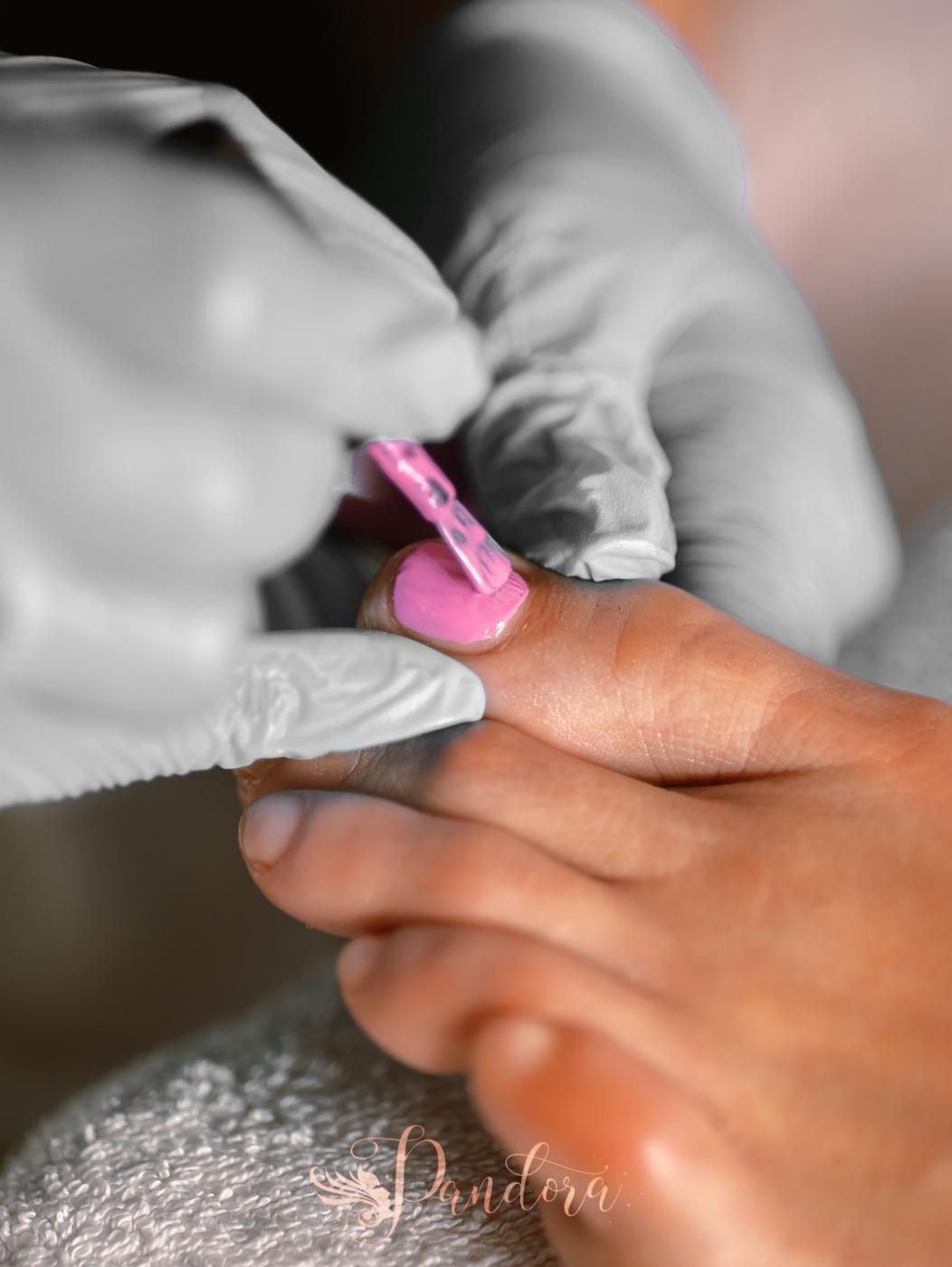 Detailed view of a pedicure session with pink nail polish applied by a beautician wearing gloves — Pandora Nail Spa, Lafayette, CA