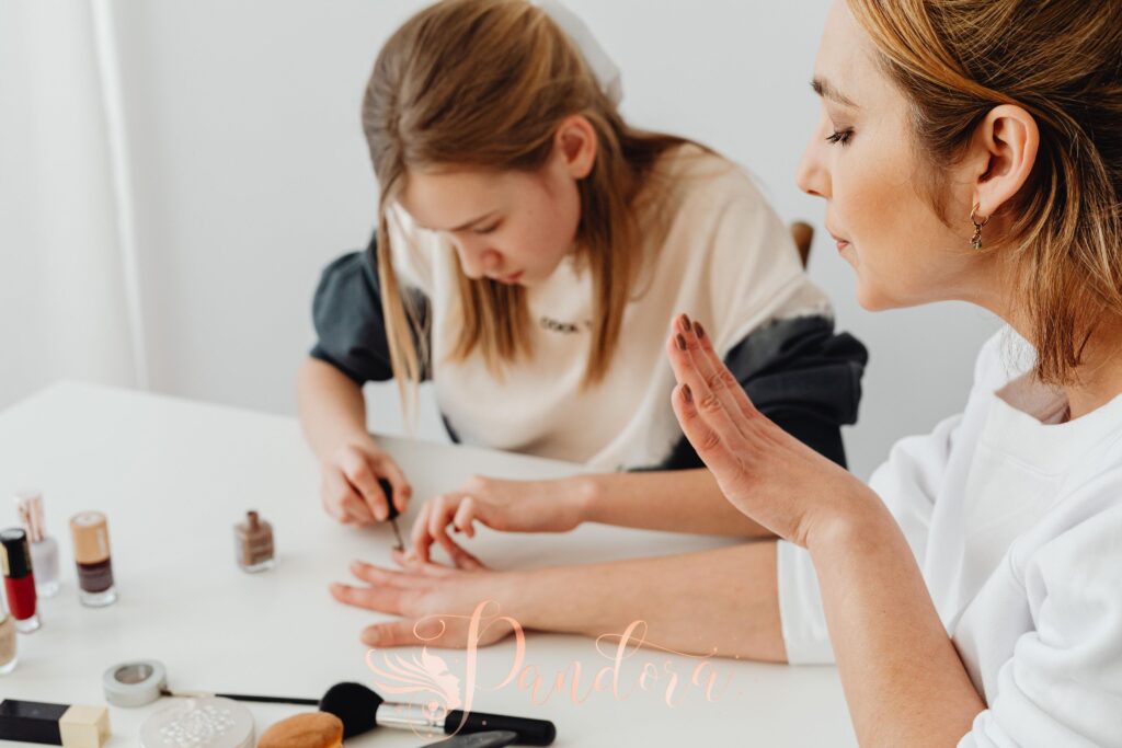 A young girl paints a woman's nails during a home manicure session at a table — Pandora Nail Spa, Lafayette, CA