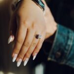 Close-up of a manicured hand showcasing a sparkling diamond ring in natural lighting — Pandora Nail Spa, Lafayette, CA