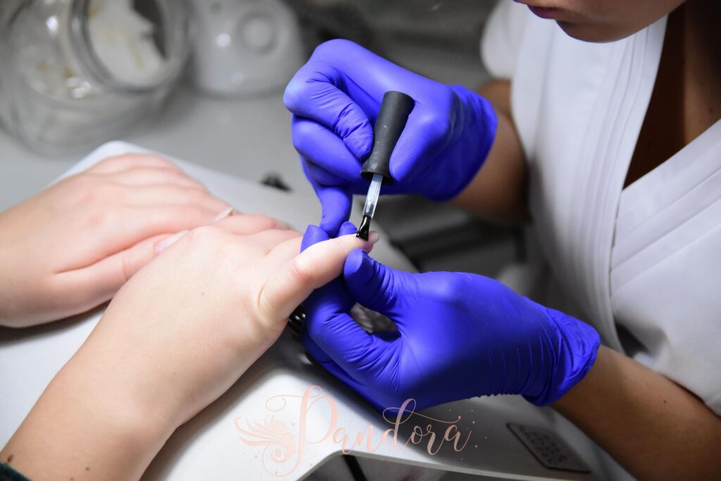 Close-up of a manicurist applying nail polish wearing purple gloves in a salon — Pandora Nail Spa, Lafayette, CA