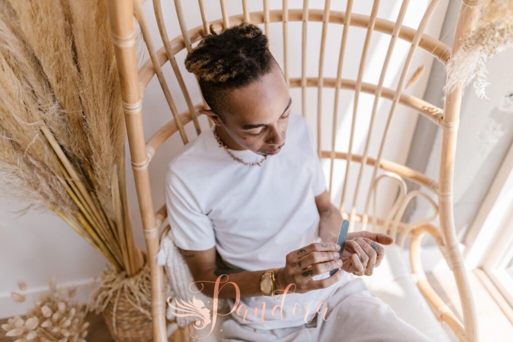 A man filing his nails while relaxing in a wicker chair indoors — Pandora Nail Spa, Lafayette, CA