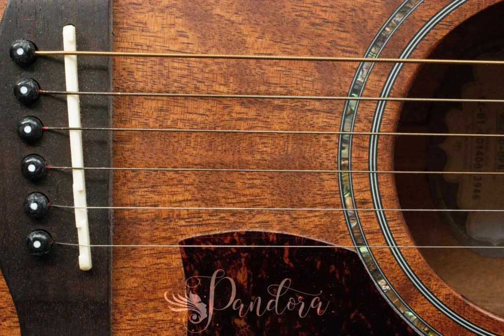 Detailed close-up of an acoustic guitar, showcasing strings and wood texture — Pandora Nail Spa, Lafayette, CA