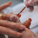 Detailed view of orange nail polish application during a manicure, showcasing precision and care — Pandora Nail Spa, Lafayette, CA