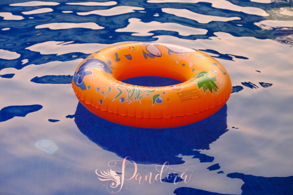 Orange inflatable ring floats on water in a sunlit pool, perfect for summer relaxation — Pandora Nail Spa, Lafayette, CA