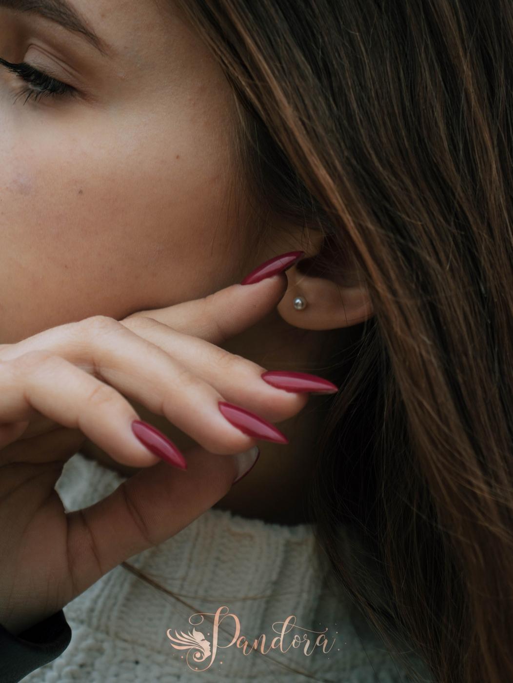 Detailed close-up of a woman with pearl earring and painted red nails, showcasing elegant jewelry — Pandora Nail Spa, Lafayette, CA